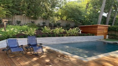 Un jardin avec piscine et chaises longues.