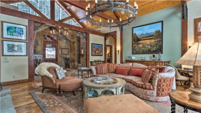 Luxurious living room with a large chandelier, plush sofas, and rustic decor.