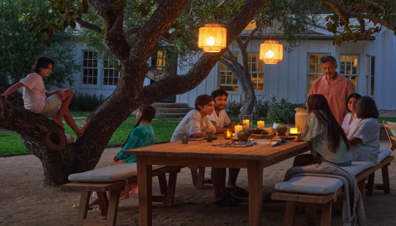 A family sitting at an outdoor table having food and drink in the evening