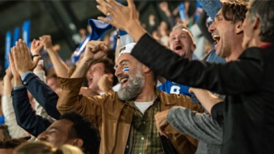 A group for people cheering and rooting for their team in a stadium.