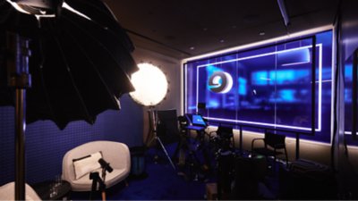 Inside of the Blue Room podcast studio setup with lighting, chairs, and a large screen displaying Expedia Group branding.