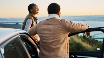 A man and woman looking out to the ocean from a cliffside.