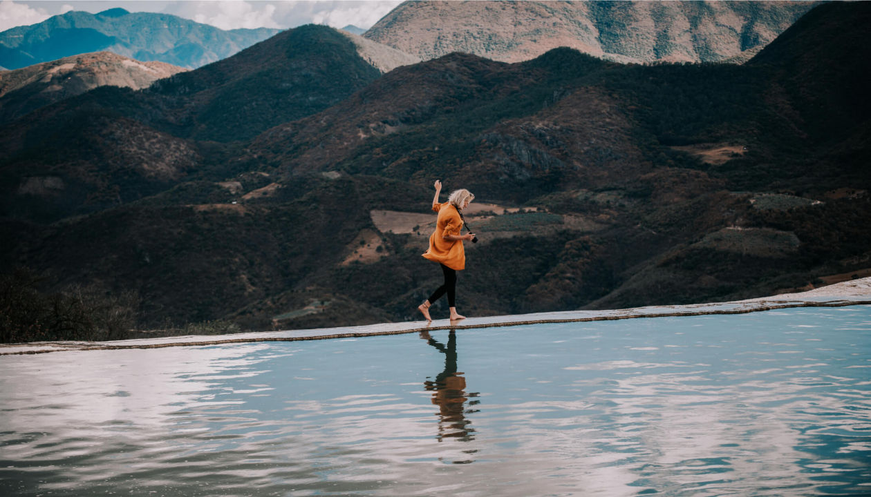 Eine Frau balanciert am Rand eines Teichs