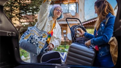 Two women unloading luggage from the trunk of their car.