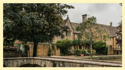 Traditional stone manor house surrounded by trees and garden on a cloudy day