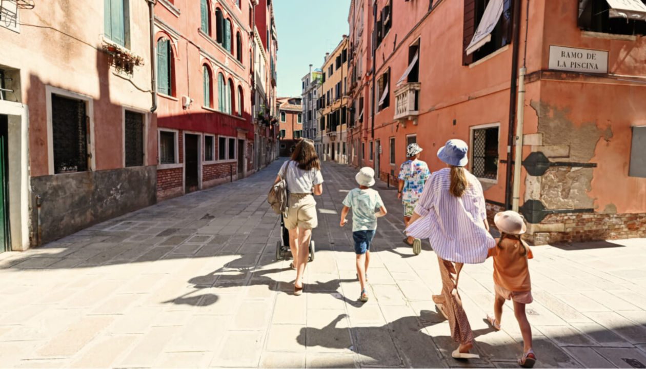 A family walks down the old road of a small city while on vacation