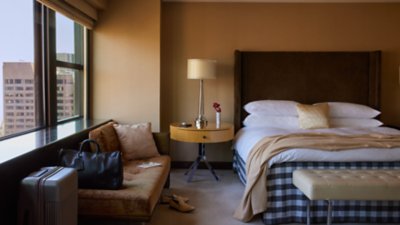  ベッド、ソファ、旅行用のスーツケースがある宿泊施設の客室。