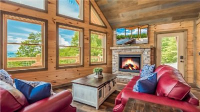 A living room with wooden floors, walls and ceiling, filled with furniture and a fireplace