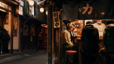 Travellers sitting and eating at a food stall at night in Shinjuku City, Tokyo.