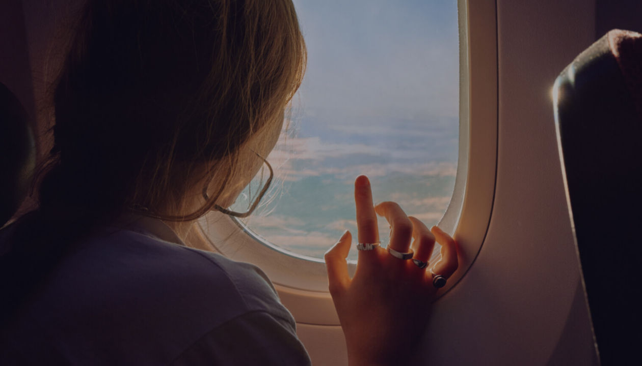 Frau blickt von ihrem Fensterplatz im Flugzeug aus nach draußen