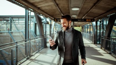 Uomo che guarda il cellulare mentre cammina su una passerella