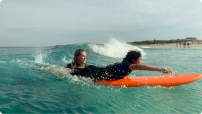 Eine junge Person hat Spaß bei einem Surfkurs