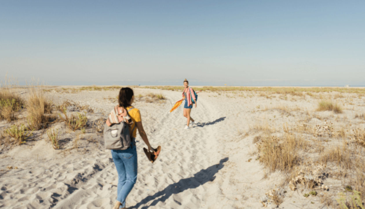 Two people walking on a sandy beach trail