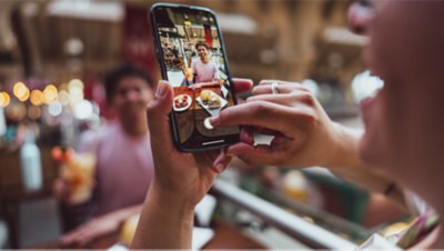 Un couple de touristes se prend en photo avec un téléphone portable dans un restaurant.