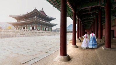 Visitors wearing traditional hanbok dresses walking at a historic Korean palace with wooden architecture