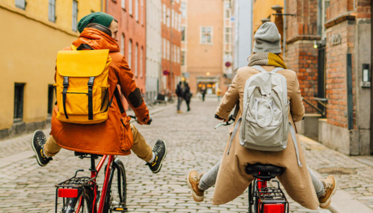 Duas pessoas felizes andando de bicicleta em uma rua de paralelepípedo