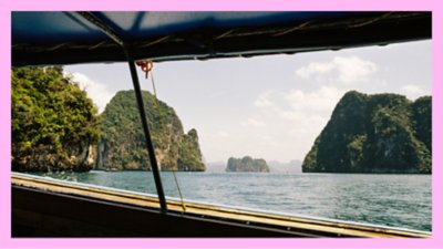 Photograph from the side of a boat in a tropical ocean with multiple green islands close by.