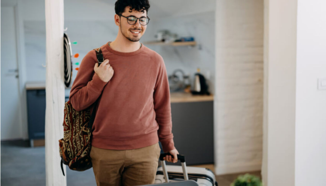 Smiling man with luggage arriving at his vacation rental