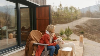 A woman and a dog sit on a patio outside a home