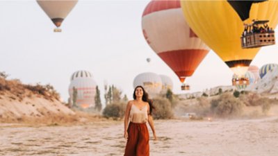woman on holiday surrounded by hot air balloons.