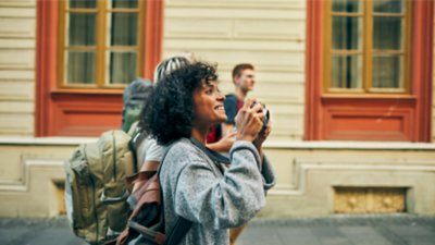 African American woman touring and photographing a foreign city with a group of tourists.